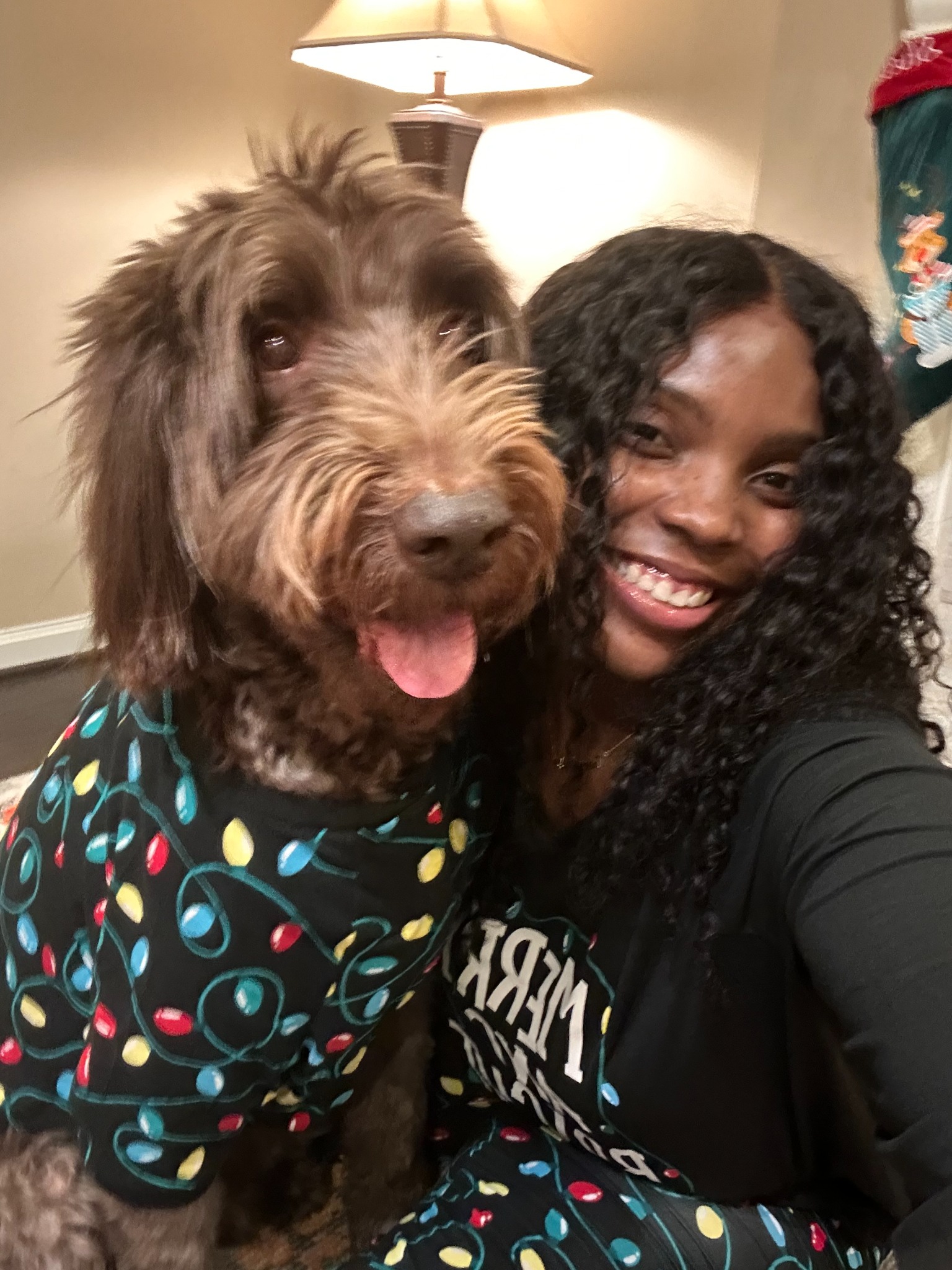 Temisha smiling beside Max, her brown labradoodle.
